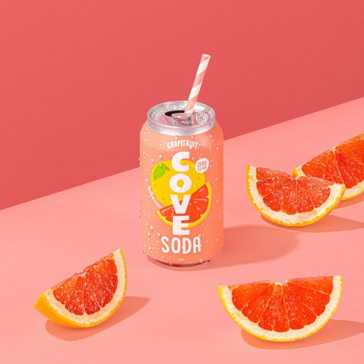A Cove Grapefruit can with a straw beside fresh grapefruit slices