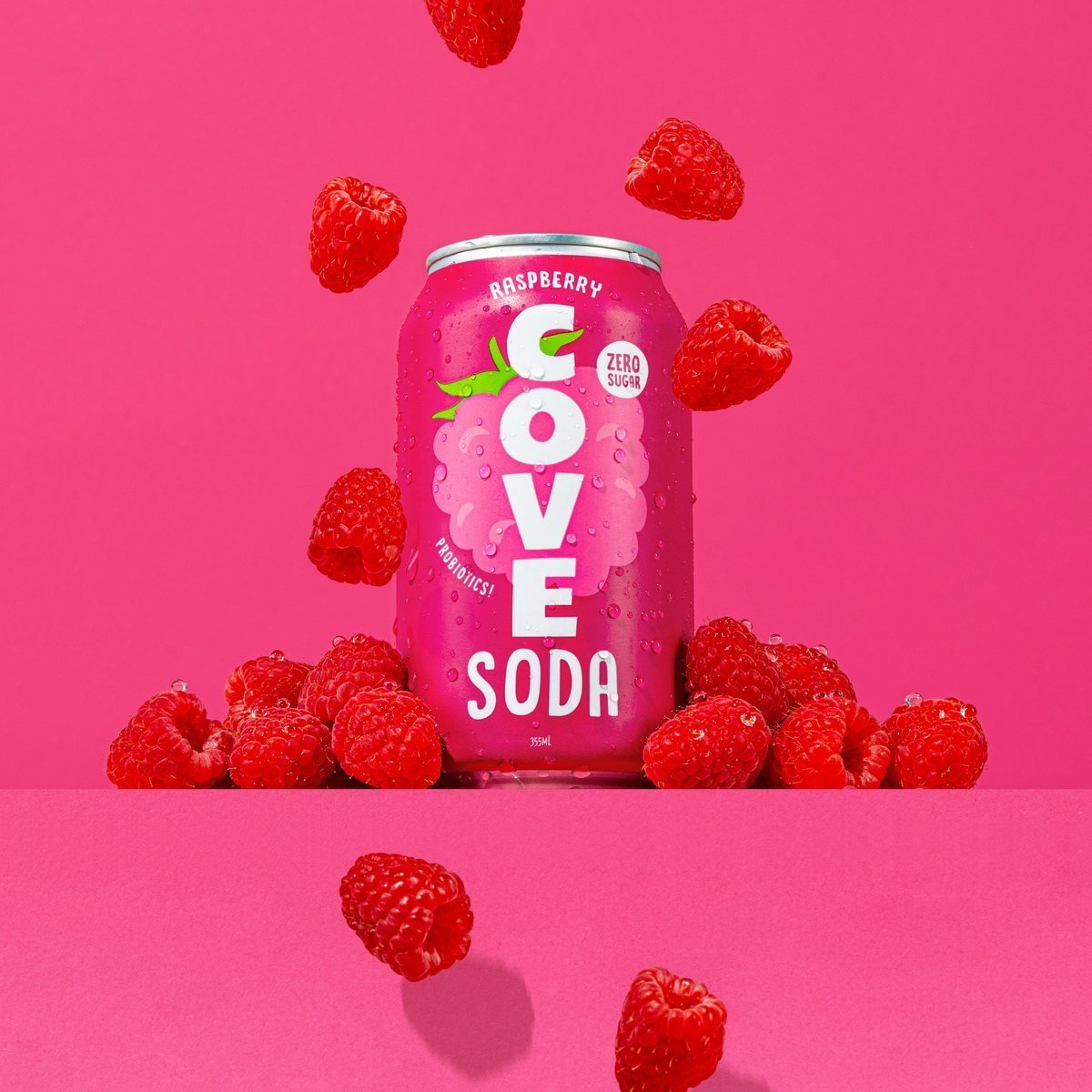 A Cove Raspberry can with fresh raspberries falling around it