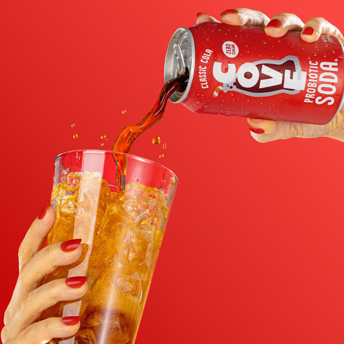 Cove Classic Cola pouring into an ice-filled glass against a red backdrop