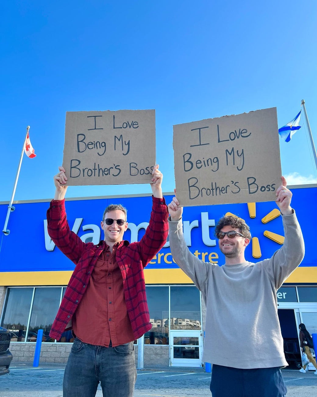 The two brothers holding matching ‘I Love Being My Brother’s Boss’ signs
