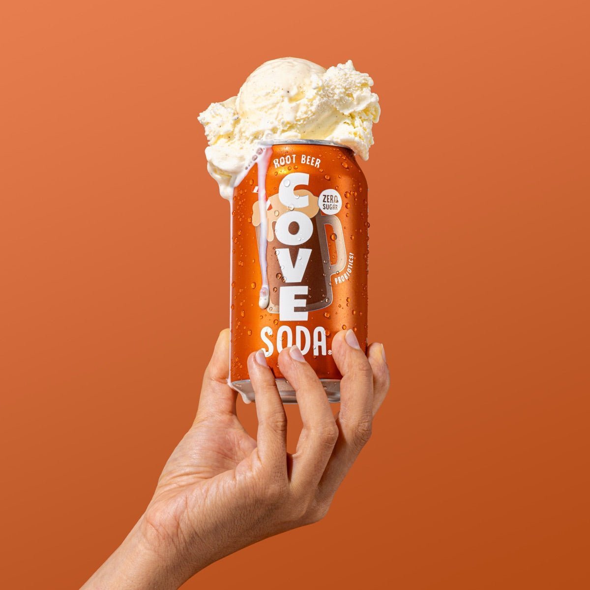 Hand holding a frosty Cove Root Beer can topped with melting vanilla ice-cream scoops